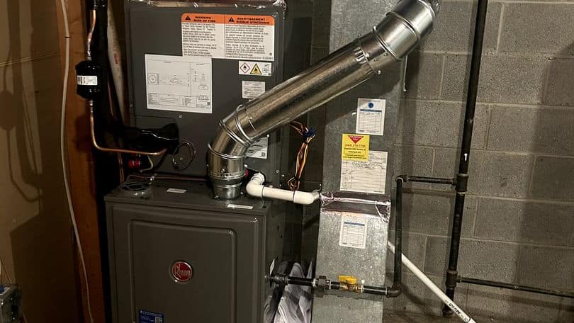Furnace fitted with a new stainless steel flue elbow in a basement